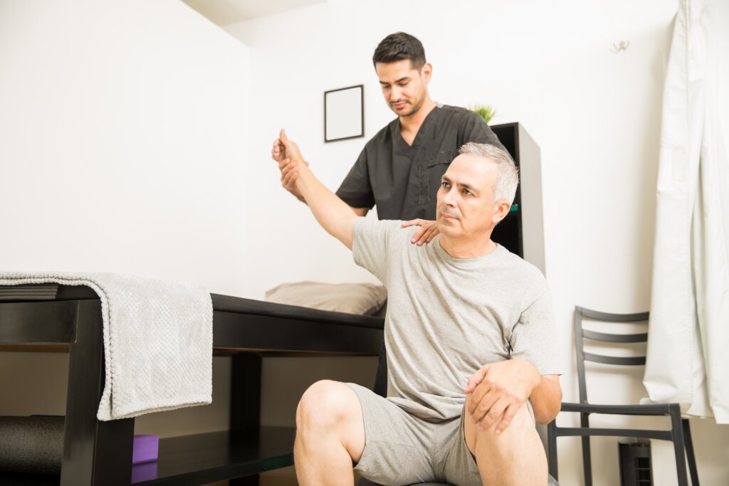 Physiotherapist helping elderly patient with hand exercises at home in Dubai – Bridges Speech Center.